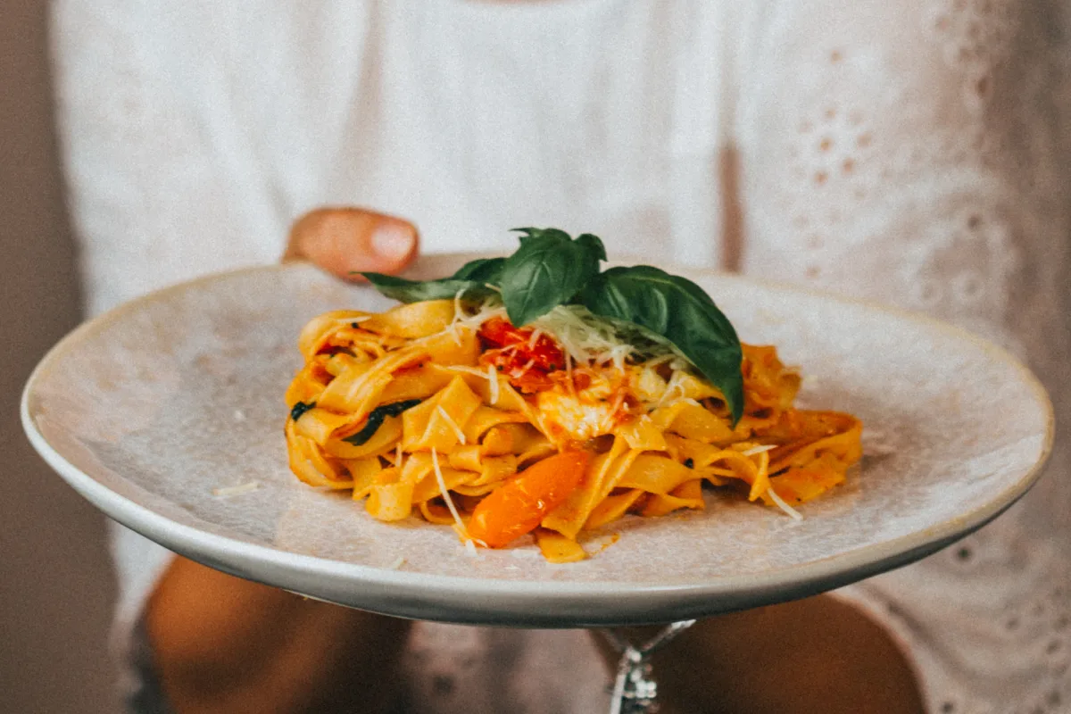 Gyönyörűen tálalt Arraibata Tagliatelle bazsalikommal és friss paradicsommal